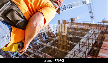 Operator, worker is holding industrial remote, wireless, console to control overhead crane with joystick at construction site. Stock Photo
