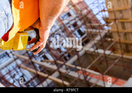 Operator, worker is holding industrial remote, wireless, console to control overhead crane with joystick at construction site. Stock Photo