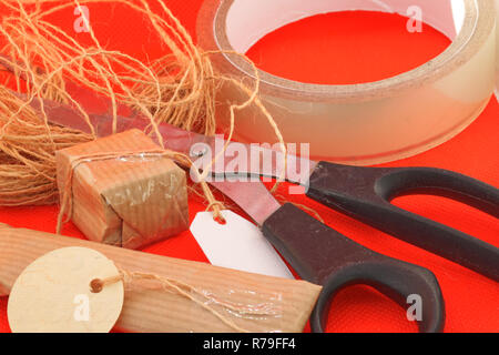 Wrapping Christmas presents with brown paper, string ans scissors Stock Photo