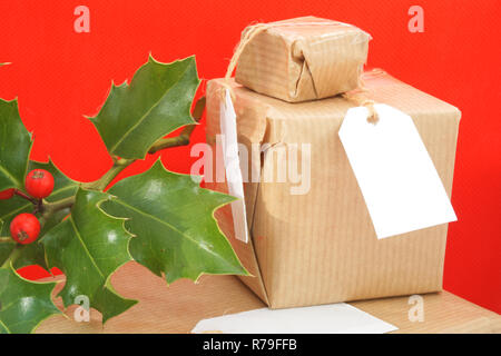 Traditionally wrapped Christmas gifts with a sprig of holly Stock Photo