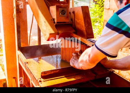 Worker is using power tool to makes clean precise cut in red brick, block. It uses abrasive action to slice through material as the saw rotates at hig Stock Photo