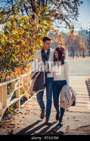 Beautiful, young couple is spending nice day in the autumn park, looking peacfully while hugging Stock Photo