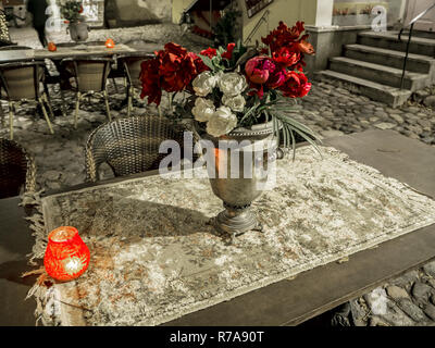 Old pre-war antique wicker furniture, shabby chic exterior. Set of round table with flowers and two chairs in the street in the old town. Table on caf Stock Photo