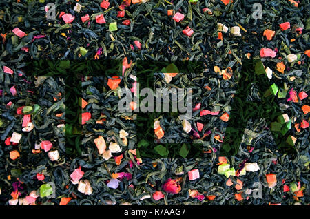 Dry green tea with flowers and pieces of fruit. Inscription on the background of tea, top view Stock Photo