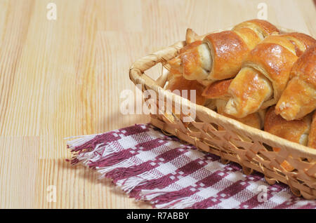 Wicker basket with home-made fresh croissants on wooden table Stock Photo