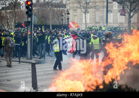 Paris, France. 8th Dec 2018. Protesters seen holding a French flag near the Arc De Triomphe during a 'Yellow Vest' protest in Paris. Without any political affiliation, the ‘Yellow Vest’ movement rallies in various cities in France this saturday against taxes and rising fuel prices. Credit: SOPA Images Limited/Alamy Live News