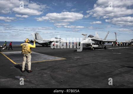 ATLANTIC OCEAN (April 10, 2017) Lt. Cmdr. Fernando Byrd, flight deck officer, directs an F/A-18C Hornet assigned to the Wildcats of Strike Fighter Squadron (VFA) 131 on the flight deck of the aircraft carrier USS Dwight D. Eisenhower (CVN 69) (Ike). Ike and its carrier strike group are underway participating in a sustainment exercise designed to maintain deployment readiness as part of the Optimized Fleet Response Plan (OFRP). Stock Photo
