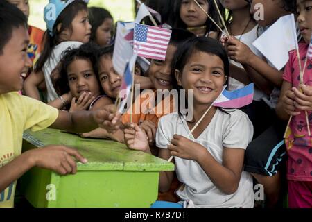 Children wave U.S. and Philippine flags during a community relations event for Balikatan 2017 in Ormoc City, Leyte, May 2, 2017. Philippine and U.S. service members hosted a community health engagement and community relations event for Ormoc City. Balikatan is an annual U.S.-Philippine bilateral military exercise focused on a variety of missions, including humanitarian assistance and disaster relief, counterterrorism, and other combined military operations. Stock Photo