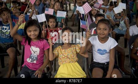 Smiling children wave Philippine and U.S. flags during Balikatan 2017 at Don Carlos Elementary School in Ormoc City, Leyte, May 2, 2017. Philippine and U.S. service members hosted a cooperative health engagement and community relations event for Ormoc City residents. Balikatan is an annual U.S.-Philippine bilateral military exercise focused on a variety of missions, including humanitarian assistance and disaster relief, counterterrorism, and other combined military operations. Stock Photo