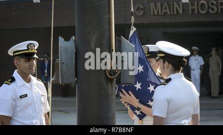 Lt. jg. Tigran Sadoian, Lt. jg. Caylin Schultz, and Ens. Sara Phipps, nurses, perform morning colors during a ceremony celebrating Nurses Week, May 10, 2017. NHCL Officers, Sailors and Civilians gathered in formation to observe the ceremony. Stock Photo