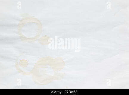 Full frame background of faded coffee cup stains on an old and uneven white paper sheet. Stock Photo