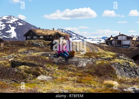 girl hiker sitting on a background of an old traditional wooden houses in Tyin, Norway