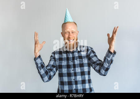 Birthday Concept. Mature man in cap standing isolated on grey hands up laughing joyful Stock Photo
