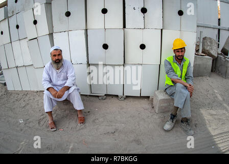 Two building Workers relaxing at a building site in Dubai, UAE Stock Photo