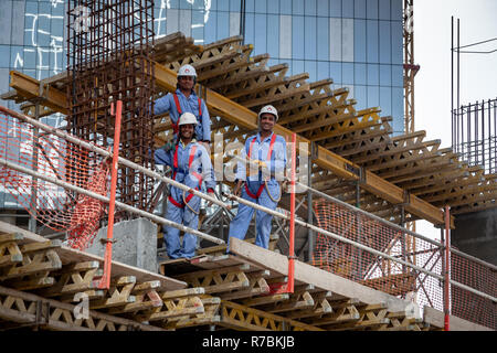Three building workers up on scaffold on building site in Dubai Stock Photo