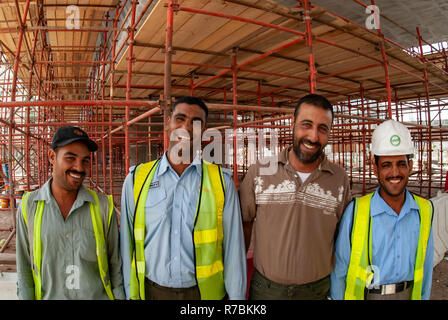 4 happy construction workers relax during a break on a building site in Dubai, UAE Stock Photo