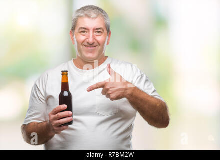 Handsome senior man drinking beer bottle over isolated background very happy pointing with hand and finger Stock Photo