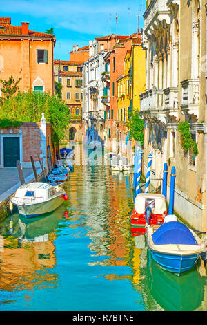 Picturesque side canal with moored motorboats in Venice, Italy Stock Photo