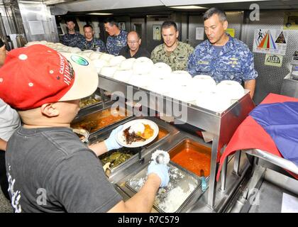 (POLARIS POINT, Guam) May 16, 2017 -- Civilian merchant mariners serve lunch to Rear Adm. Stephen Williamson, Director of Fleet Maintenance, U.S. Pacific Fleet, and Capt. Douglas A. Bradley, submarine tender USS Emory S. Land (AS 39) Commanding Officer, during a shipboard tour, May 16. Williamson toured the ship and other repair facilities in Guam to assess current maintenance operations and capabilities. Land and USS Frank Cable (AS 40), the U.S. Navy’s only two submarine tenders, are both homeported in Apra Harbor, Guam, and provide maintenance, hotel services, and logistical support to subm Stock Photo