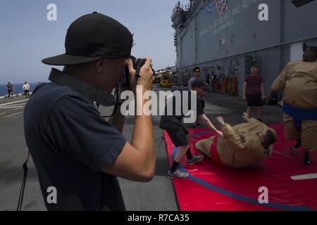 U.S. 5TH FLEET AREA OF OPERATIONS (May 5, 2017) Seaman Kai Vinson takes photos of a sumo wrestling game during a steel beach picnic aboard the amphibious assault ship USS Bataan (LHD 5). The ship is currently deployed with the Bataan Amphibious Ready Group in support of maritime security operations designed to reassure allies and partners and preserve the freedom of navigation and the free flow of commerce in the region. Stock Photo