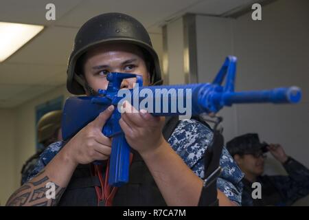 NORFOLK (May 4, 2017) Aviation Ordnanceman 3rd Class Arwin Palma, from Las Vegas, Nevada, assigned to the aircraft carrier USS George Washington’s (CVN 73) security reaction force, watches the perimeter inside of the ship’s floating accommodation facility during an anti-terrorism training team evolution involving an active shooter drill. George Washington is homeported in Norfolk preparing to move to Newport News, Virginia for the ship’s refueling and complex overhaul (RCOH) maintenance. Stock Photo