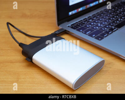 portable external disk drive connected to laptop by wire. data backup information concept Stock Photo