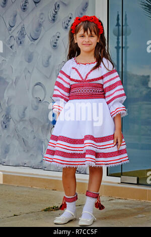 Nesebr, Bulgaria - 13 June, 2013: small dark-haired girl with flowers on her head is standing in a national dance costume. Traditional embroidery in B Stock Photo