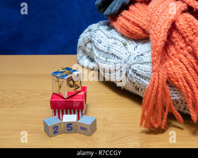 25 December cubes and small gift boxes next to pile of winter apparel. banner concept for seasonal Christmas sale Stock Photo