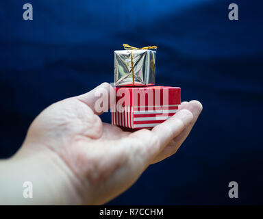 streched hand with two small gift boxes on blue background Stock Photo