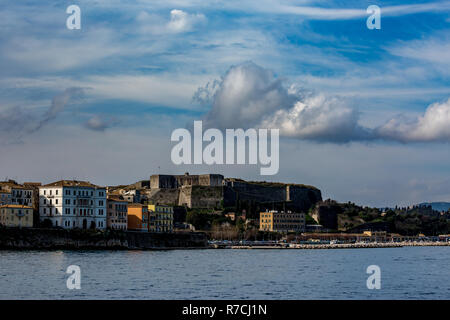 Beautiful scenery spring landscape of Kerkira island, Corfu, Greece with dramatic cloudy blue sky and calm sea waters as seen from the ferryboat line  Stock Photo