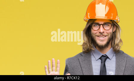 Young handsome architec man with long hair wearing safety helmet over isolated background showing and pointing up with fingers number ten while smilin Stock Photo
