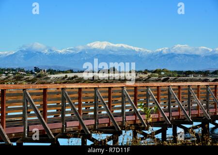 Wooden bridge at the Bolsa Chica Wetlands in Huntington Beach, CA with snow-capped Mt. Baldy in the background. Stock Photo