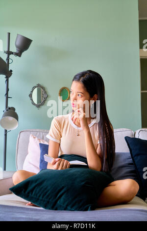 Beautiful woman posing - sitting, cross legged and thinking Stock Photo