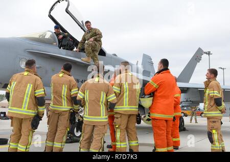 U.S. Air Force Senior Master Sgt. Jeremy Wohlfore, Air National Guardsman with the Alpena Combat Readiness Training Center, Michigan, provides a quick emergency egress class on the F/A-18 Hornet jet to Latvian firefighters while the jet is being refueled on the airfield, May 18.  Wohlfore has routinely made trips to Leilvarde since 2008 to provide training to members of the Latvian air force to enhance their capabilities.  Latvia is Michigan's State Partnership Program partner, a program designed to promote interoperability and stability in Baltic nations since 1993. Stock Photo