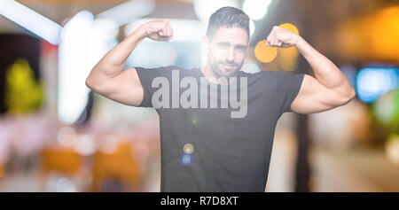 Young handsome man over isolated background showing arms muscles smiling proud. Fitness concept. Stock Photo