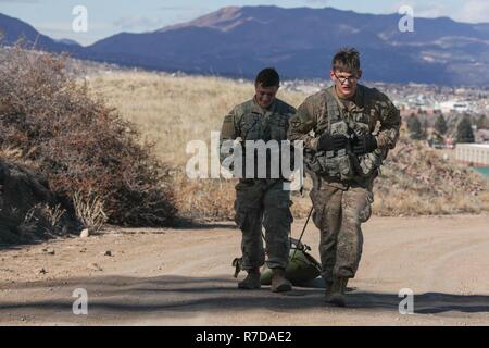 1st Lt. Jeremy Matsumoto and Capt. Erwin Marciniak, assigned to Headquarters and Headquarters Company, 299th Brigade Engineer Battalion, 1st Stryker Brigade Combat Team, 4th Infantry Division, drag a 200 pound Skedco stretcher uphill during the Best Sapper Competition, Fort Carson, Colorado, November 29, 2018. This year’s competition includes nine two-person teams from units across Fort Carson. The top three teams will go on to compete in the Army-wide Best Sapper Competition in April 2019. Stock Photo