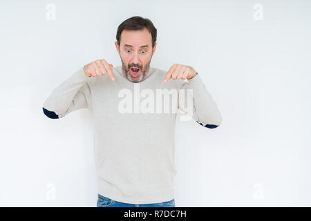 Elegant senior man over isolated background Pointing down with fingers showing advertisement, surprised face and open mouth Stock Photo