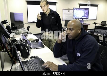 U.S. Army Staff Sgt. Rayshod Thompson, administrative noncommissioned officer, 33rd Civil Support Team, District of Columbia National Guard talks to fellow unit members about their locations while U.S. Army 1st Lt. John Hemby, operations officer, 34th Civil Support Team, Virginia National Guard, places a radio call to check their statuses in Washington D.C., December 5, 2018. The joint operation center was the center for operations during the 33rd and 34th CSTs mobilization for former President George H.W. Bush's state funeral. Stock Photo