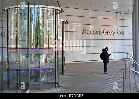 Visitor outside revolving door entrance to modern Bernard Weatherill House council offices building with Access Croydon sign South London England UK Stock Photo