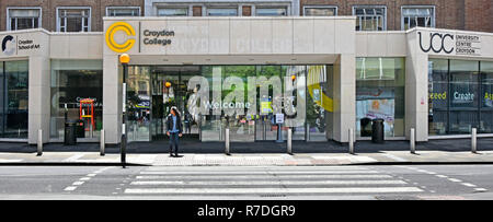 A person beside Belisha beacon & Pedestrian crossing outside entrance & welcome sign at Croydon College campus education buildings London England UK Stock Photo