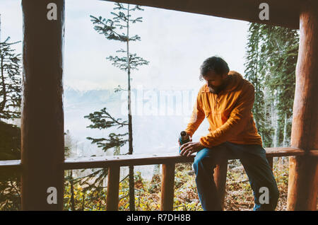 Traveler man relaxing alone in forest with thermos drinking tea Travel adventure lifestyle outdoor vacations journey Stock Photo