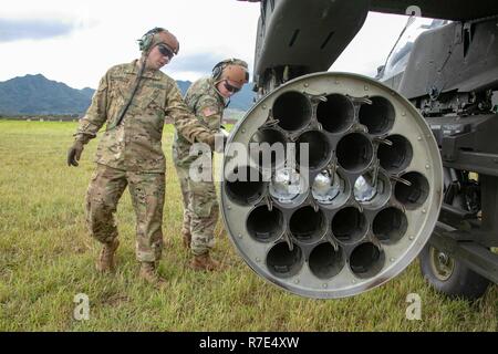 U.S. Army Soldiers assigned to 2nd Squadron, 6th Calvary Regiment, 25th Combat Aviation Brigade, 25th Infantry Division, load an aerial rocket pod on a AH-64 Apache helicopter in preparation for aerial gunnery qualification at a forward arming and refueling point on Schofield Barracks, Hi., Nov. 29, 2018. An Apache has a 2.75-inch aerial rocket system, primarily used as an area weapon system for use against enemy personnel and equipment and can carry up to four 19-shot launcher pods on four wing store pylons, for a total of 76 rockets. Stock Photo