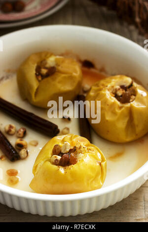 Baked apples with raisins, hazelnuts and cinnamon on wooden background. Rustic style. Stock Photo