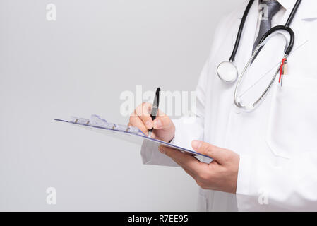 Close up of doctor's hands writing on medical chart. Stock Photo