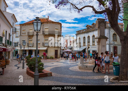 Lagos, Portugal - June 27, 2018: Tourists stop at stores lined along the tiled streets of Lagos on a sunny day. Stock Photo