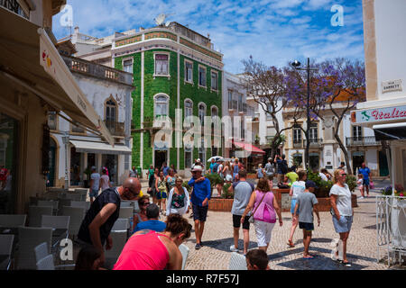 Lagos, Portugal - June 27, 2018: Tourists stop at stores lined along the tiled streets of Lagos on a sunny day. Stock Photo