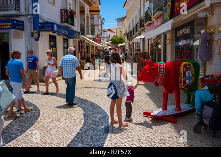 Lagos, Portugal - June 27, 2018: Tourists stop at stores lined along the tiled streets of Lagos on a sunny day. Stock Photo