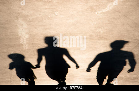 Blurry shadow of parents and daughter walking on summer promenade Stock Photo