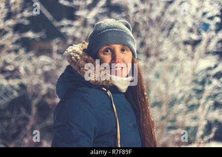 Smiling girl at night on a background of trees in winter. Toned vintage photo Stock Photo