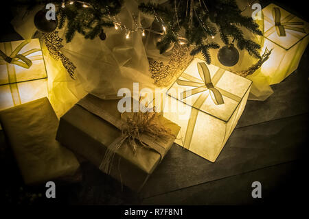 A bunch of lit presents under a Christmas tree Stock Photo